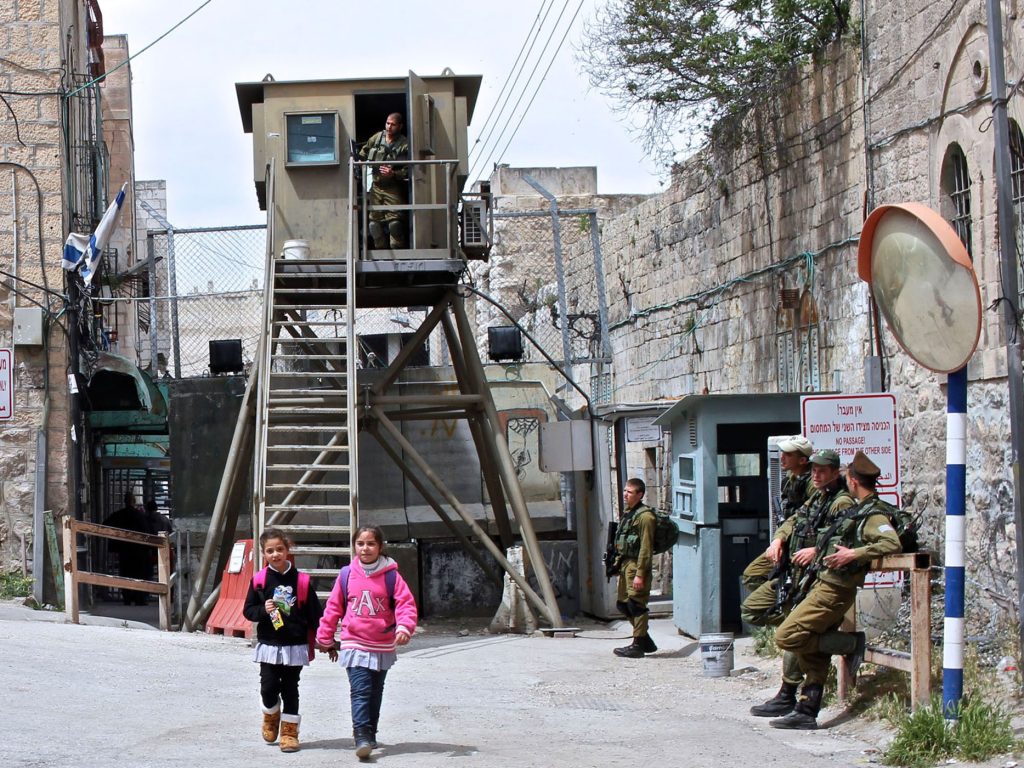 دو کودک دانش‌آموز فلسطینی در حال عبور از یک ایست بازرسی ارتش اسرائیل در الخلیل